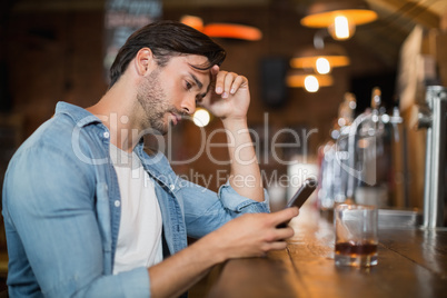 Upset man using mobile at pub
