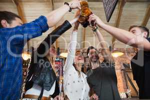 Cheerful friends toasting beer bottles and mugs
