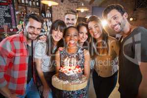 Portrait of happy friends holding birthday cake