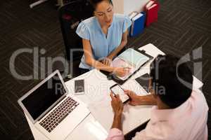 Businesswoman discussing with male colleague at desk