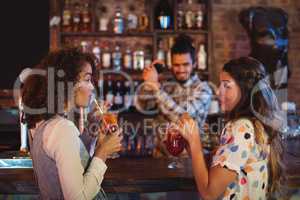 Two young women having cocktail drinks at counter