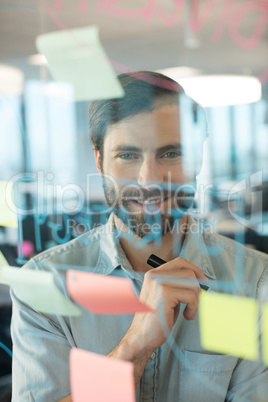Smiling businessman looking through plans written on glass