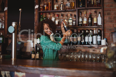 Female bartender mixing a cocktail drink in cocktail shaker