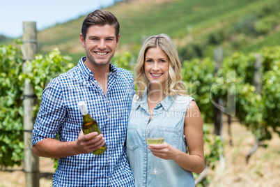 Portrait of young couple holding wine bottle and glass