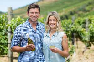 Portrait of young couple holding wine bottle and glass