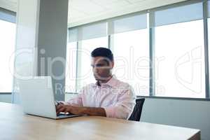 Serious businessman using laptop in conference room