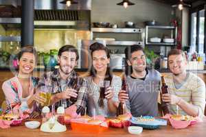 Portrait of cheerful friends holding beer in restaurant