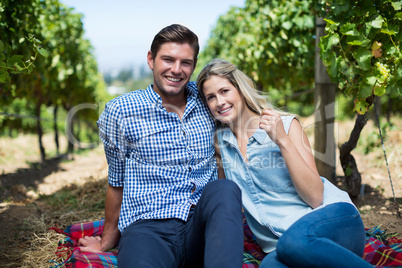 Happy young couple sitting together at vineyard