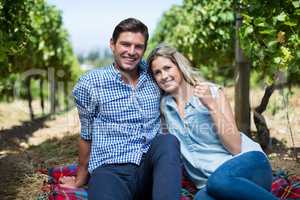 Happy young couple sitting together at vineyard