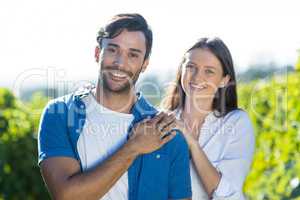 Portrait of happy young couple standing at vineyard