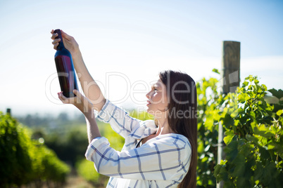 Side view of woman holding wine bottle at vineyard