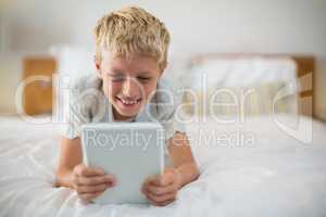 Smiling boy using digital tablet on bed