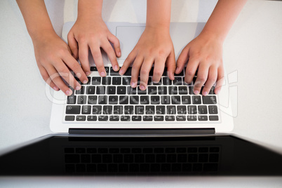 Siblings hand using laptop in kitchen