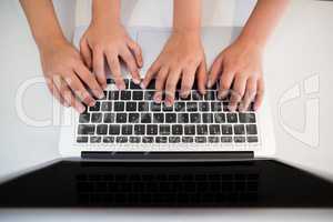 Siblings hand using laptop in kitchen