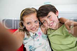 Siblings taking selfie in living room