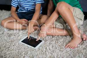 Siblings using digital tablet in living room