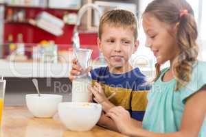 Smiling sibling having breakfast cereal in kitchen