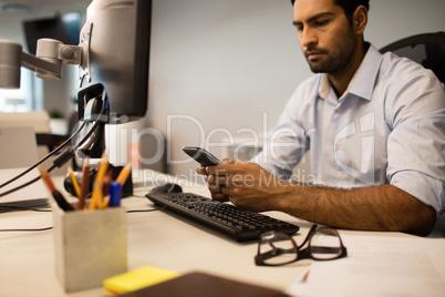 Businessman using mobile phone while sitting at office