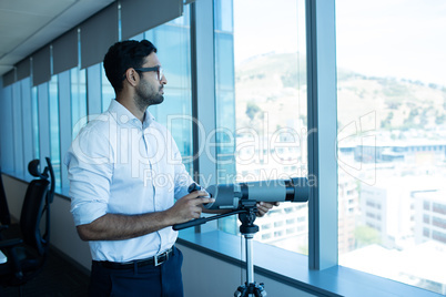 Businessman holding binoculars by glass window