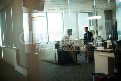 Business colleagues interacting while sitting on sofa in office