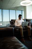 Businessman using laptop on sofa in office