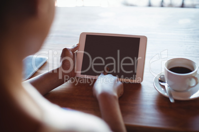 Woman using digital tablet while having coffee