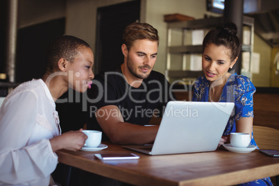 Friends using laptop while having coffee