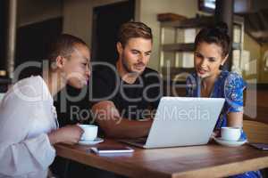 Friends using laptop while having coffee