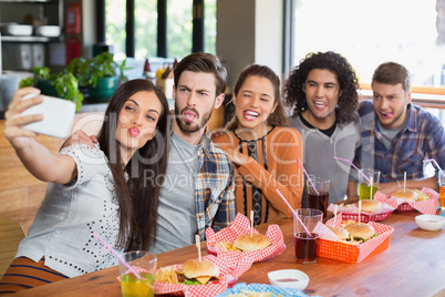 Woman taking selfie with friends in restaurant