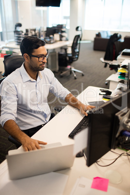 Businessman using laptop and desktop pc together