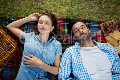 Couple sleeping on picnic blanket