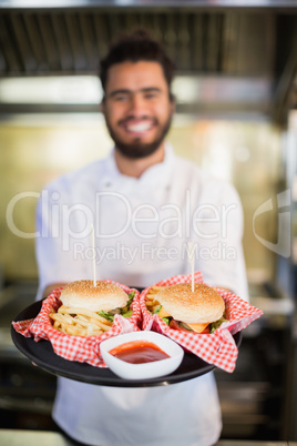 Chef holding burgers in plate at commercial kitchenc
