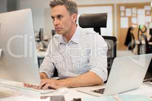 Serious businessman typing on computer in office
