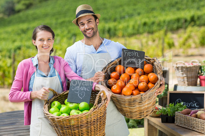 Portrait of smiling couple holding fresh fruits in wicker baskets