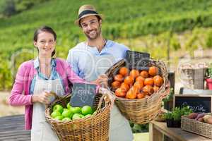 Portrait of smiling couple holding fresh fruits in wicker baskets