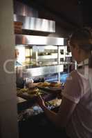 Chef passing tray with french fries and burger to waitress