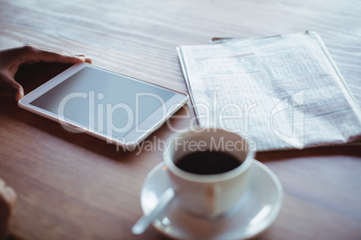 Hand of woman using digital tablet while having coffee