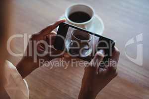 Hands of woman taking a clicking picture of black coffee