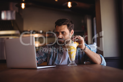 Man using laptop while having milkshake