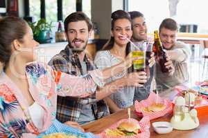 Cheerful friends enjoying beer with food at restaurant