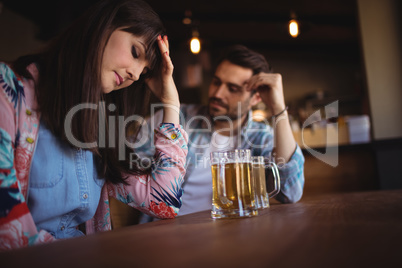 Sad couple having beer at counter