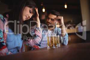 Sad couple having beer at counter