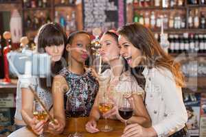 Happy female friends taking selfie in pub