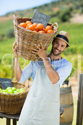 Portrait of happy farmer carrying by fresh oranges in container