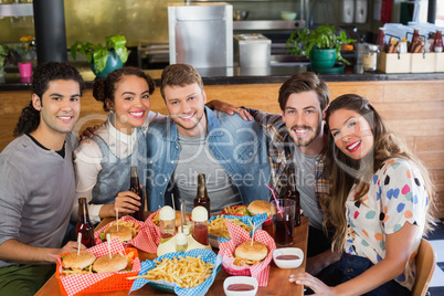 Friends sitting by food and drink served on table in restaurant