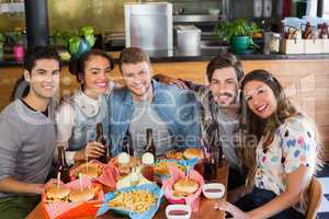 Friends sitting by food and drink served on table in restaurant