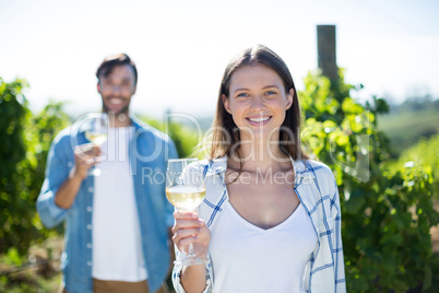 Smiling young couple posing with wineglasses at vineyard