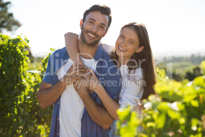 Portrait of cheerful couple embracing at vineyard