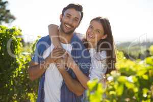 Portrait of cheerful couple embracing at vineyard