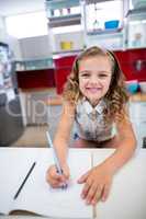 Portrait of smiling girl doing homework in kitchen